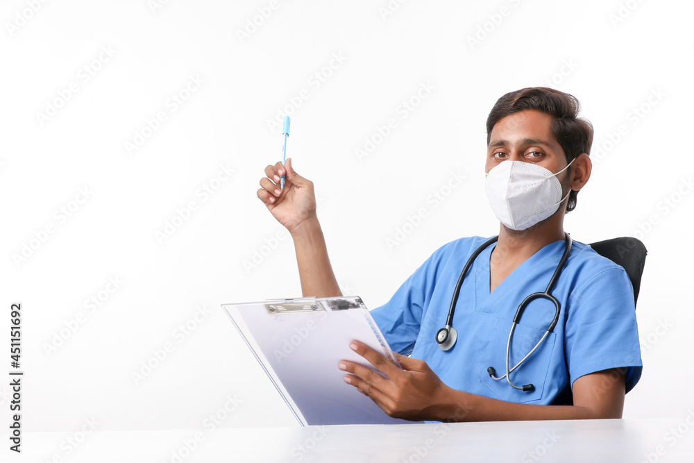 Young indian male doctor writing on notepad at clinic. Young indian male doctor writing on notepad at clinic.