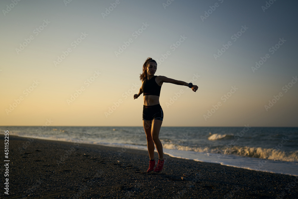 pretty young female athlete doing a workout on a sunrise in the beach