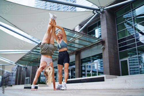 Two women doing exercise outdoors in city, healthy lifestyle concept.