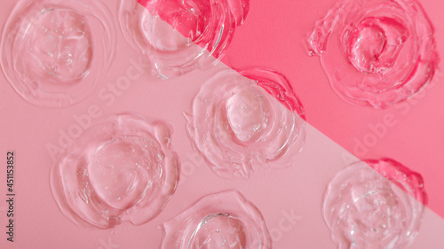 Transparent swatch gel texture on color pink background. Skincare cosmetic product texture of collagen or hyaluron liquid serum. Circle swatch made from skin care gel. Long web banner