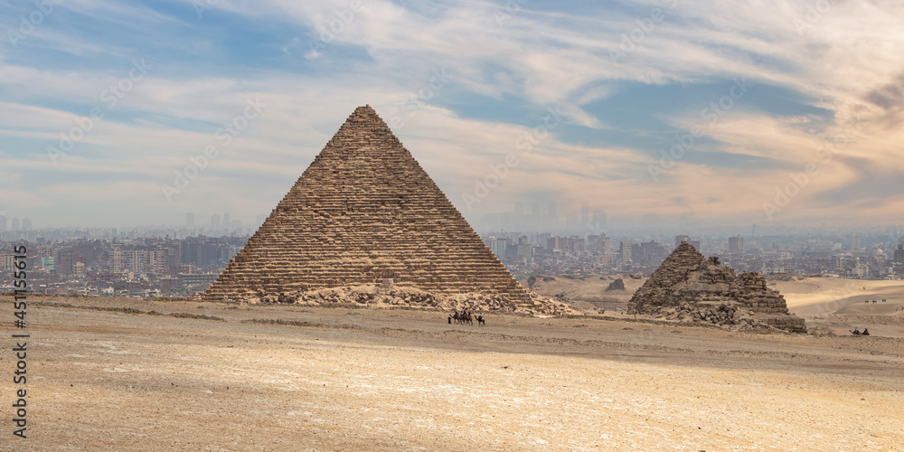 The Great Pyramid of Menkaure in the Giza, Egypt. Pyramid Complex on background Cairo city skyline with dramaric sky. The Great Pyramid of Menkaure in the Giza, Egypt. Pyramid Complex on background Cairo city skyline with dramaric sky.