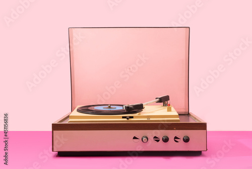 Gramophone record player from sixties. Turntable for single vinyl with pink bottom with light pink background.