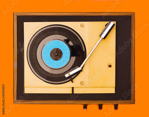 Flat lay gramophone record player from sixties. Turntable for single vinyl on orange background.
