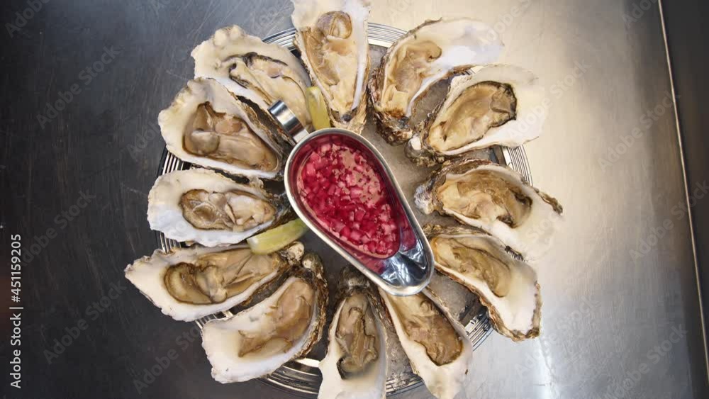 Tray of fresh served oysters on ice with lemon rotating on large salver plate for luxury restaurant visitors. Traditional meditarian dish sea food set for gourmets. Tray of fresh served oysters on ice with lemon rotating on large salver plate for luxury restaurant visitors. Traditional meditarian dish sea food set for gourmets.
