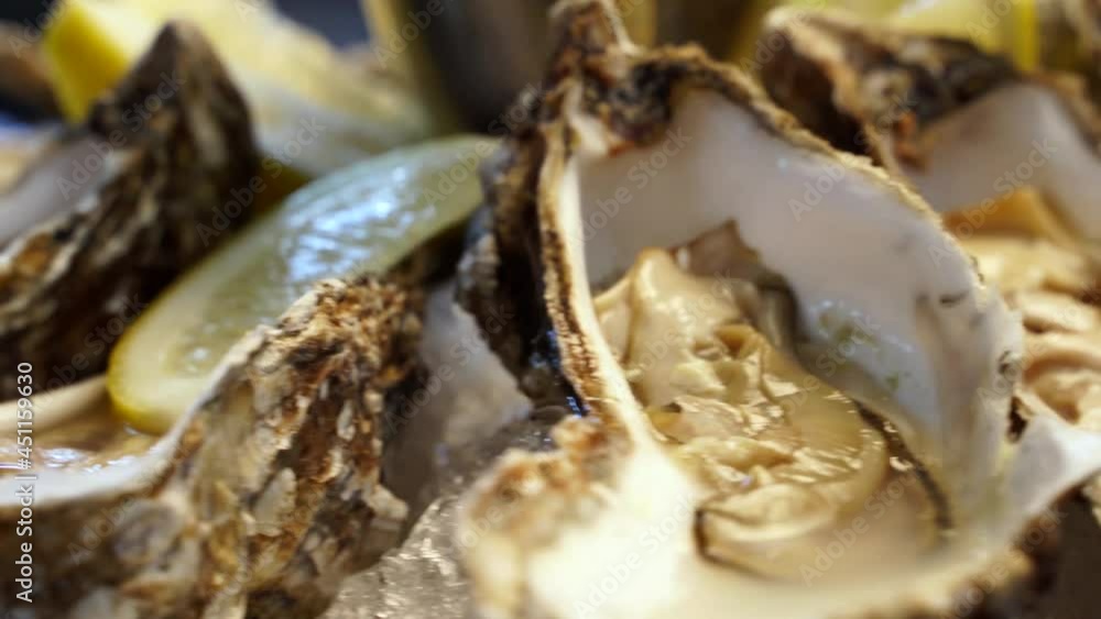 Tray of fresh served oysters on ice with lemon rotating on large salver plate for luxury restaurant visitors. Traditional meditarian dish sea food set for gourmets. Tray of fresh served oysters on ice with lemon rotating on large salver plate for luxury restaurant visitors. Traditional meditarian dish sea food set for gourmets.