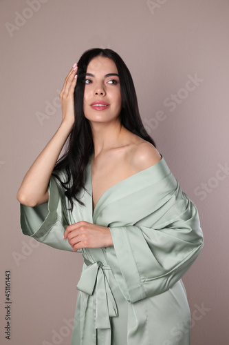 Sexy young woman in light silk robe on beige background
