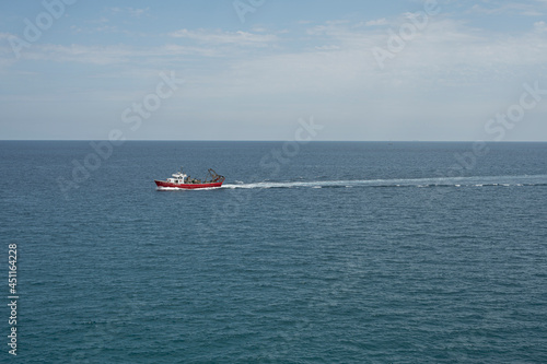 Barcelona, ​​Spain; August 15, 2021: Small fishing boat sailing through the sea near the shore