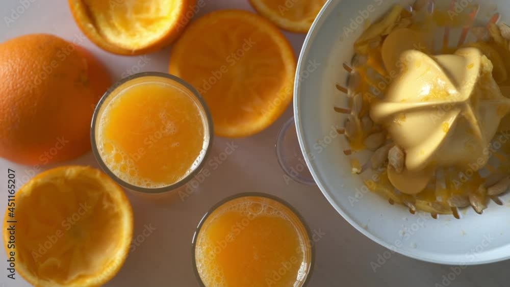 Fresh orange juice from electric juicer in three glasses and orange peel after squeezing on the table, top view. Healthy vegan ripe fruit juice, natural vitamins from food. Organic nutrition. Fresh orange juice from electric juicer in three glasses and orange peel after squeezing on the table, top view. Healthy vegan ripe fruit juice, natural vitamins from food. Organic nutrition.