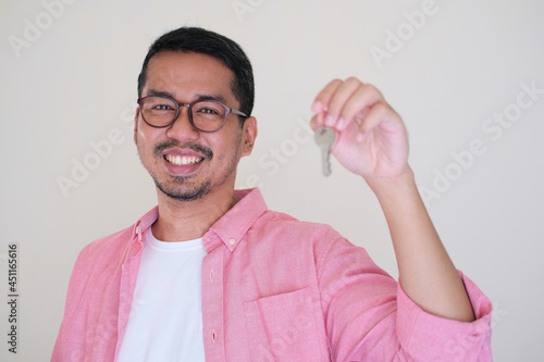 Adult Asian man smiling happy while showing his house key photo