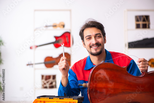 Fotografie Young male repairman repairing musical instruments at workplace
