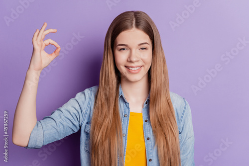 Bild auf Leinwand Happy cute girl showing ok gesture toothy smile on violet background