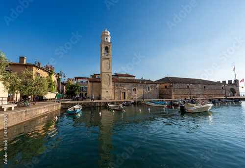 Port of the small village of Lazise, tourist resort on the coast of Lake Garda (Lago di Garda). Ancient church of San Nicolo in Romanesque style. Verona province, Veneto, Italy, southern Europe.