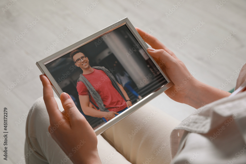 Woman holding framed photo of happy man indoors, closeup