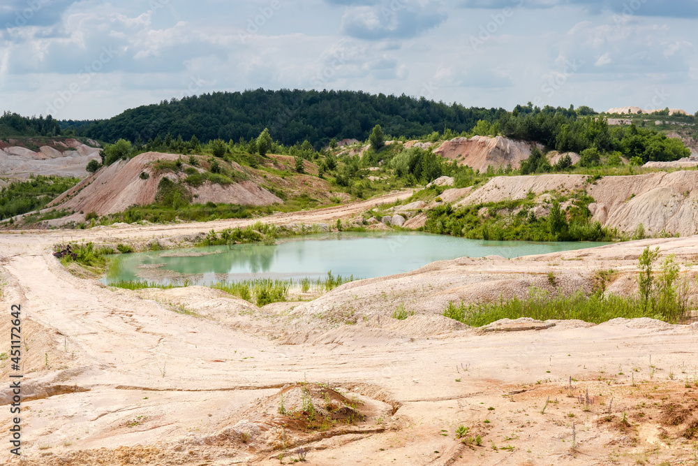Small turquoise quarry lake in abandoned kaolin pit in summer day
