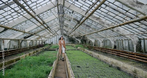 Woman in coat with flowers in socks walks in greenhouse.  photo