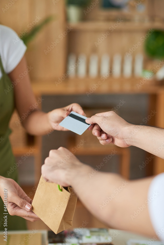 Hands of man buying handmade soap in offline store and paying with credit card