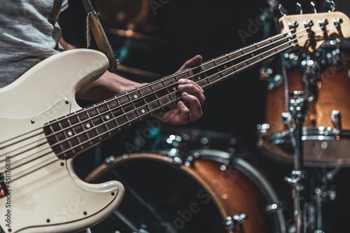 A man plays the bass guitar on a blurred background with bokeh.