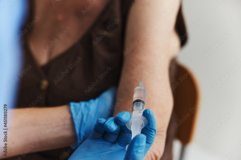 doctor makes an injection in the arm of a patient covid passport close-up