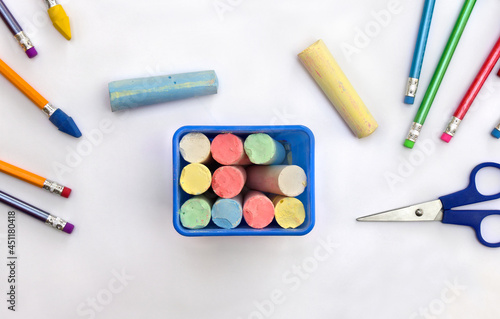 Back to School. School supplies ( blue box with crayons, pencil, eraser, scissors ) on a white background. Top view, flat lay