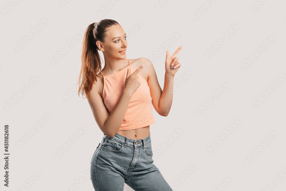 Portrait of a smiling girl pointing finger to the side at on a white isolated background. Positive woman points to an idea, a place for advertising Portrait of a smiling girl pointing finger to the side at on a white isolated background. Positive woman points to an idea, a place for advertising