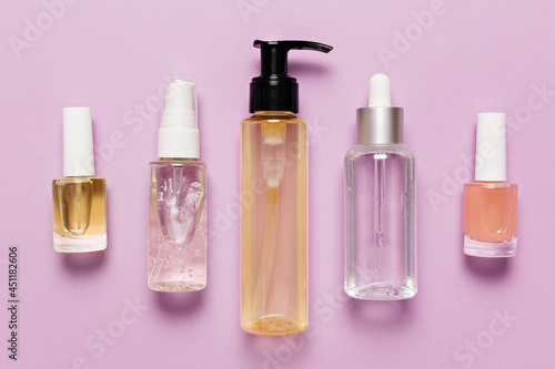 Organic cosmetics packaging design. Flat lay, top view clear glass pump bottle, brush jar, moisturizing serum jar on a purple background. Natural cosmetics SPA