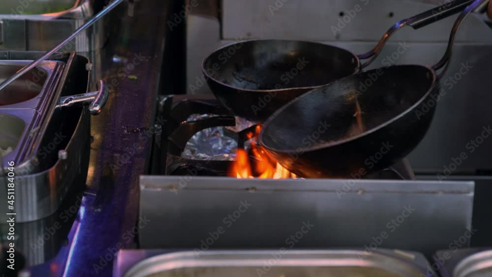 Two blackened skillets or frying pans on a gas burner with naked flame in a commercial restaurant kitchen in close up Two blackened skillets or frying pans on a gas burner with naked flame in a commercial restaurant kitchen in close up