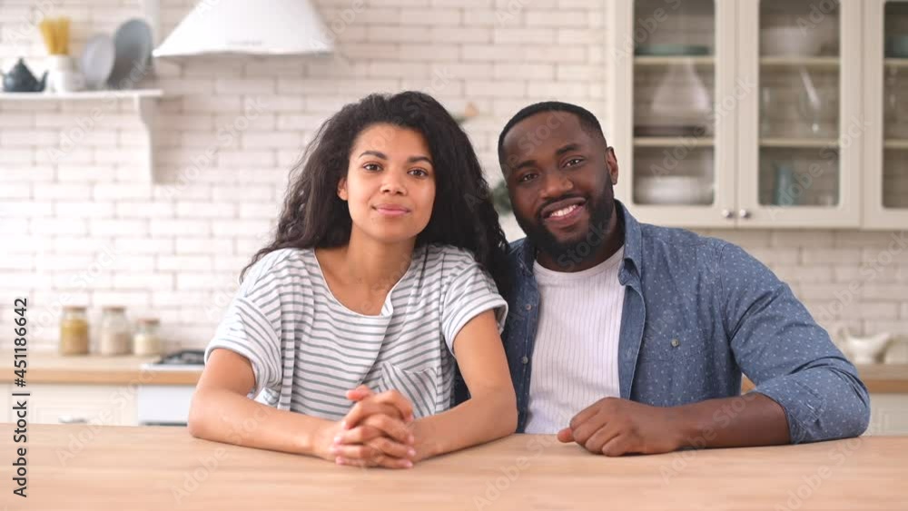 Young African American woman and man looks at the camera sitting in the kitchen, listening carefully and smiles, video chat with couple in love, webcam view Young African American woman and man looks at the camera sitting in the kitchen, listening carefully and smiles, video chat with couple in love, webcam view