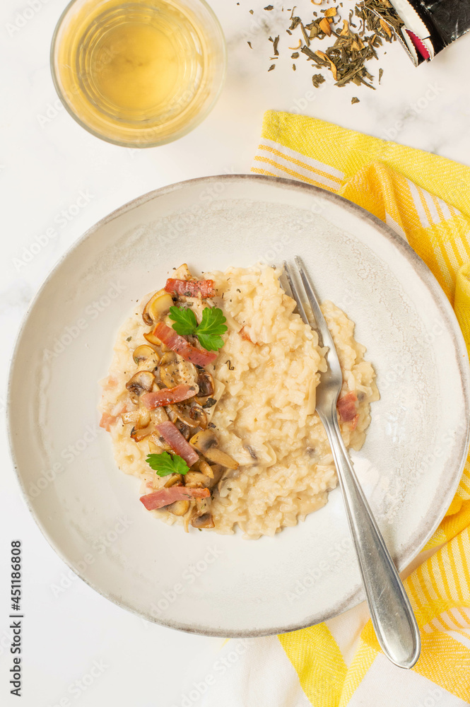 Risotto with mushrooms, green tea and italian speck. White background and yellow towel Risotto with mushrooms, green tea and italian speck. White background and yellow towel