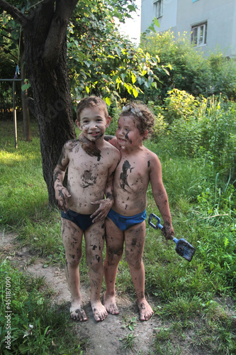 Two boys posing soiled in mud