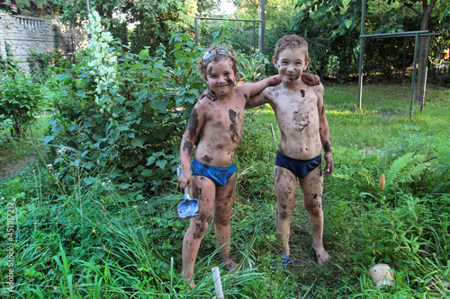 Two boys posing soiled in mud