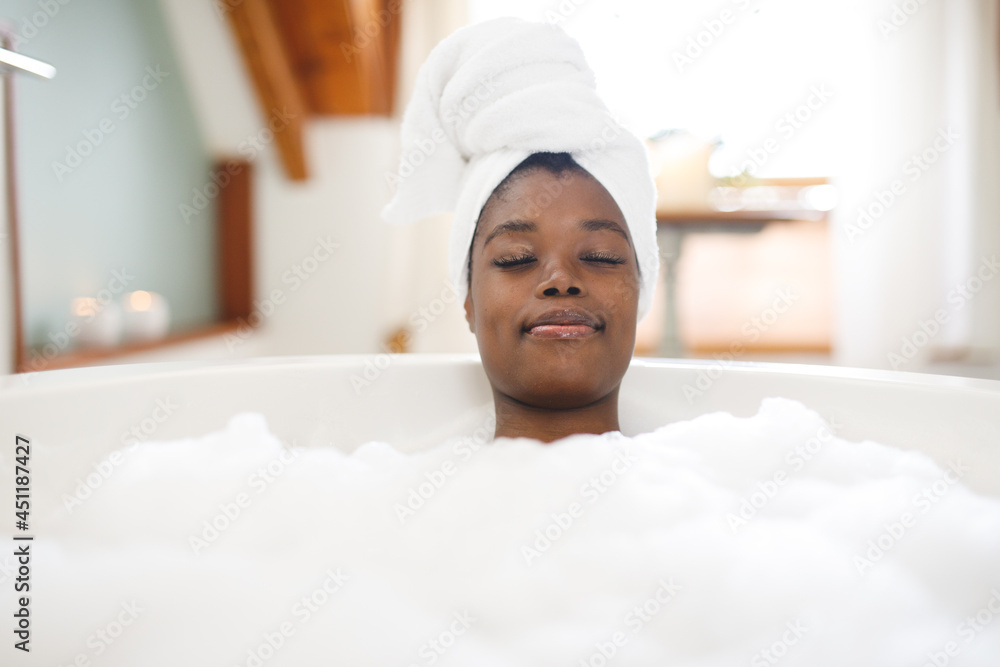 Smiling african american woman in bathroom relaxing in bath with eyes closed Smiling african american woman in bathroom relaxing in bath with eyes closed
