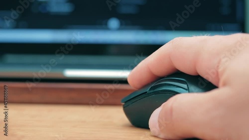 Hand uses the wireless mouse for working with laptop or computer on the desk table, extreme close up view