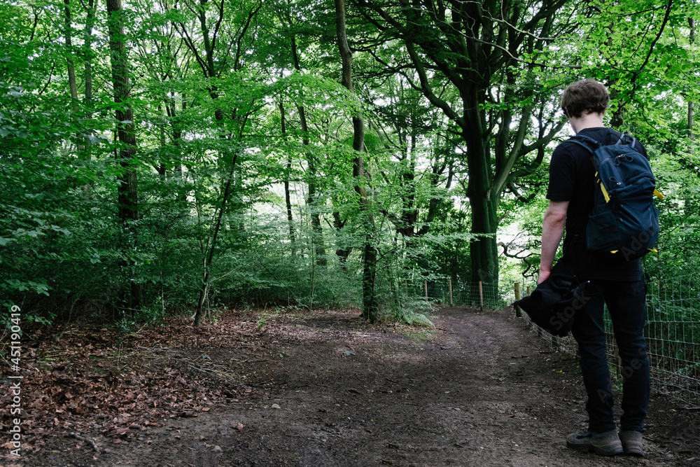 Hiker with  a backpack walking along the nature path in a forest, stone pathway, outdoor excersise.