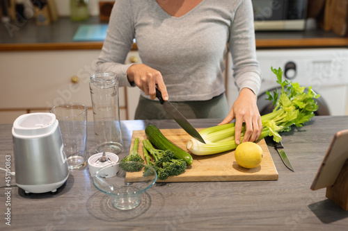 Caucasian woman in kitchen, preparing health drink, chopping vegetables