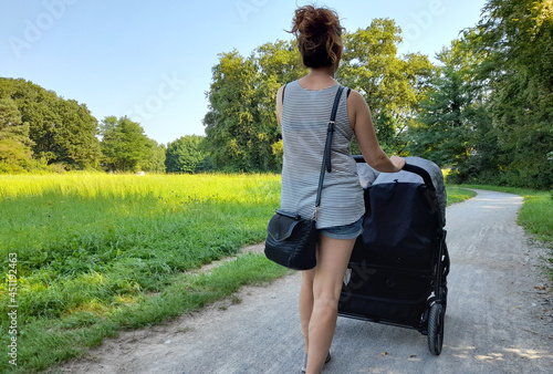 Giovane donna che passeggia con i suoi gemelli nel parco in estate photo