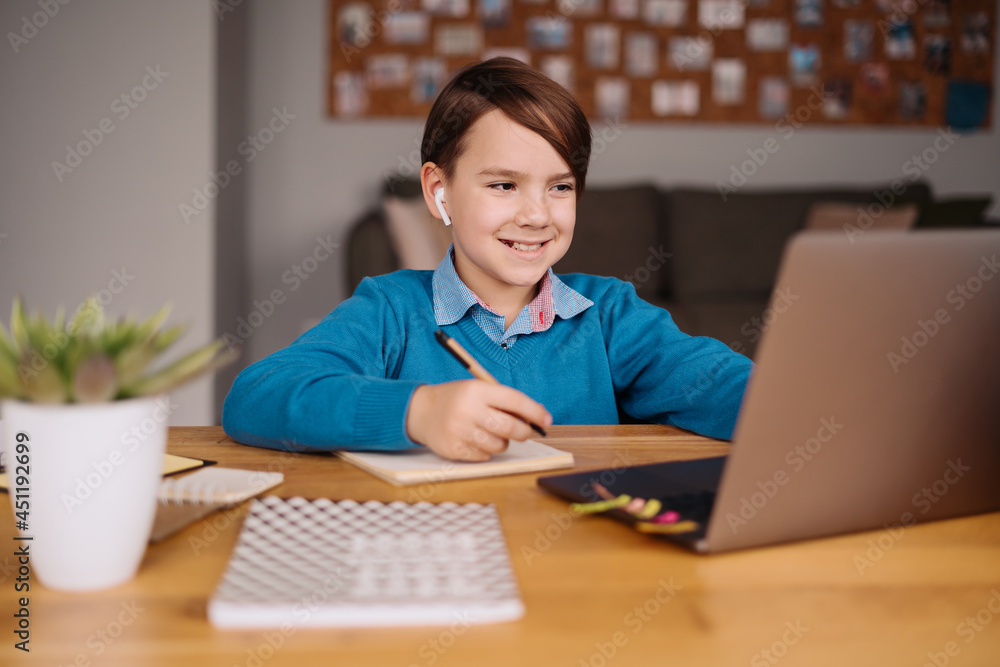 A Preteen boy uses a laptop to make a video call with his teacher, online classes, making notes A Preteen boy uses a laptop to make a video call with his teacher, online classes, making notes