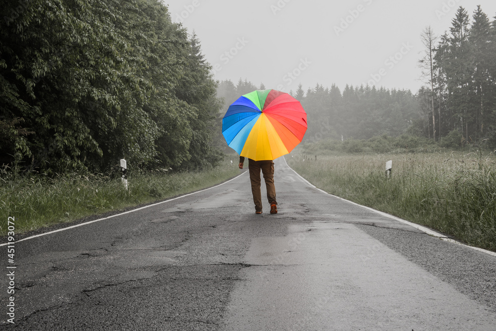 Person mit buntem Regenschirm auf einer Straße in monochromer Umgebung