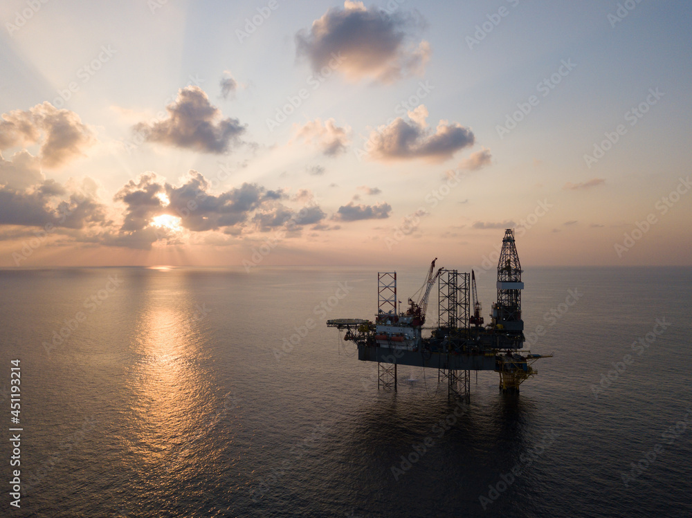 Offshore Jack Up Rig in The Middle of The Sea at Sunset Time for Petroluem Exploration and Production Offshore Jack Up Rig in The Middle of The Sea at Sunset Time for Petroluem Exploration and Production