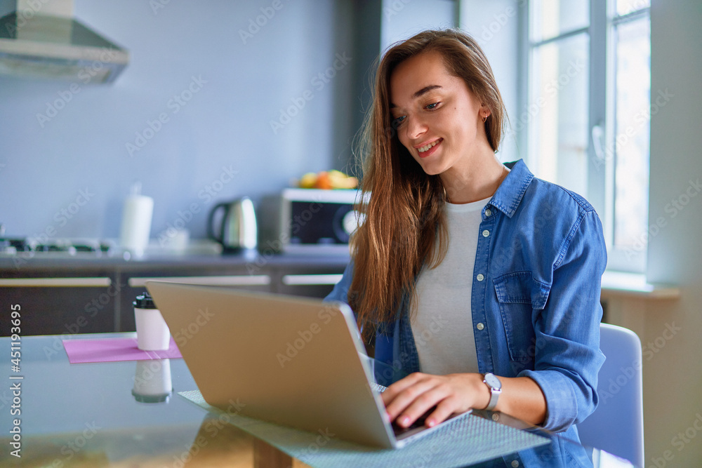 Young smiling attractive happy cute adult millennial girl freelancer remote working online on laptop at home Young smiling attractive happy cute adult millennial girl freelancer remote working online on laptop at home