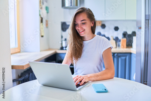 Young smiling attractive happy cute adult millennial girl freelancer remote working online on laptop at home