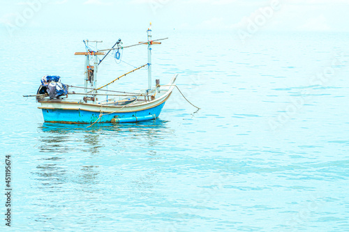 Small fishing boat floating in blue sea with blue sky
