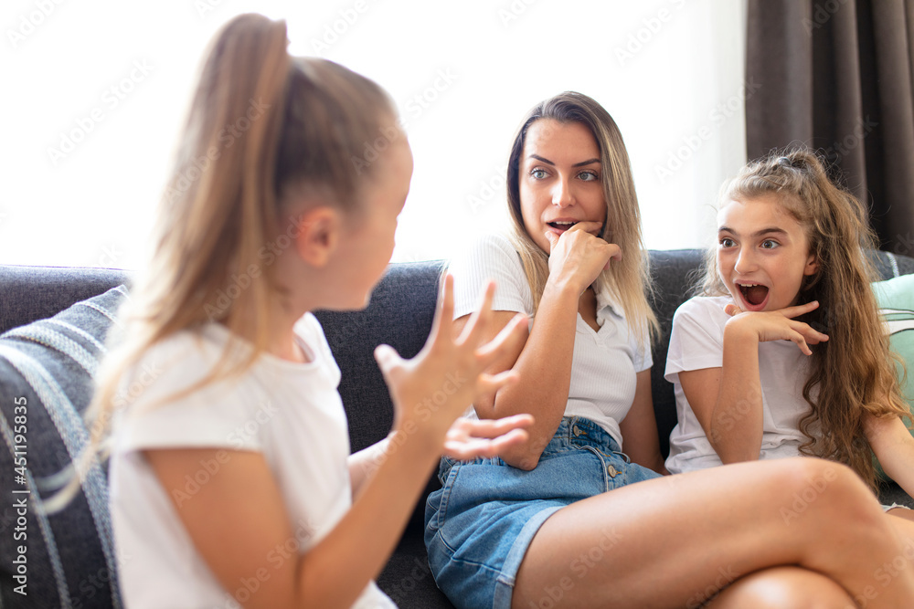 young mother and her little daughters chatting on the sofa. girls gossip hour
