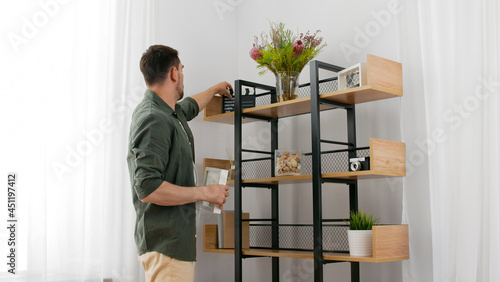 home improvement and decoration and people concept - man arranging shelf