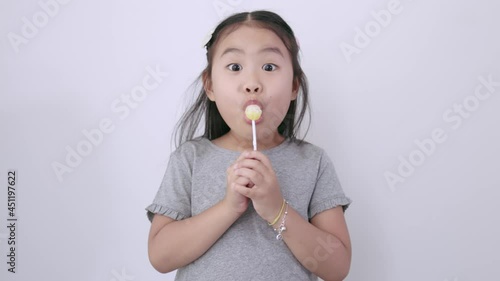 Asian girl sucking Happy lollipop on white background. Hand-held 4k slow-motion footage photo