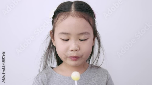 Asian girl sucking Lemon flavored lollipop with happy saliva dripping on white background.