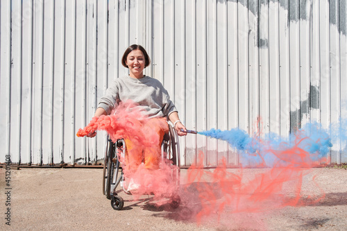 Girl with loss of leg function sitting at wheelchair and playing with bombs with smoke