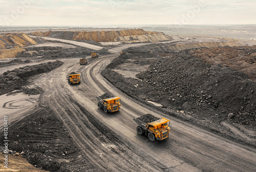 Large quarry dump truck. Big yellow mining truck at work site. Loading coal into body truck. Production useful minerals. Mining truck mining machinery to transport coal from open-pit production photo