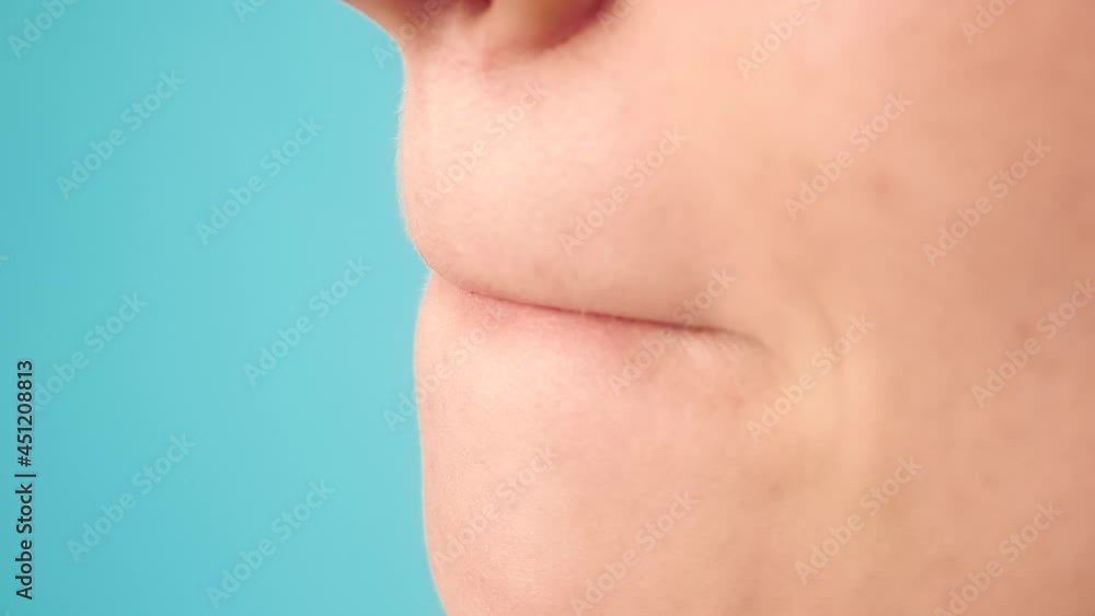 Lady with make-up applies red lipstick on lips with special brush and aligns colour on blue studio background slow motion macro Lady with make-up applies red lipstick on lips with special brush and aligns colour on blue studio background slow motion macro