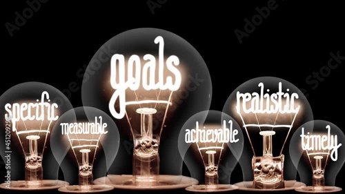 Light bulbs going from dark to light with Smart Goals fiber text on black background. High quality 4k video