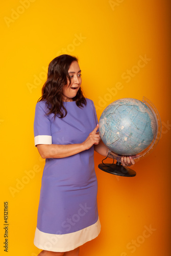 Teacher's Day, Knowledge Day. A woman in a dress on a yellow background with a globe in her hands. online education. quarantine © Marina Chernivetskay